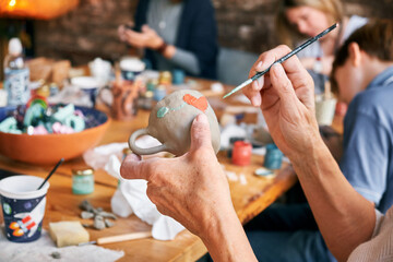 A female potter paints a ceramic mug. The process of creating clay products