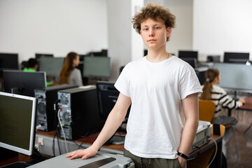 Portrait of European teenager boy standing in computer class.