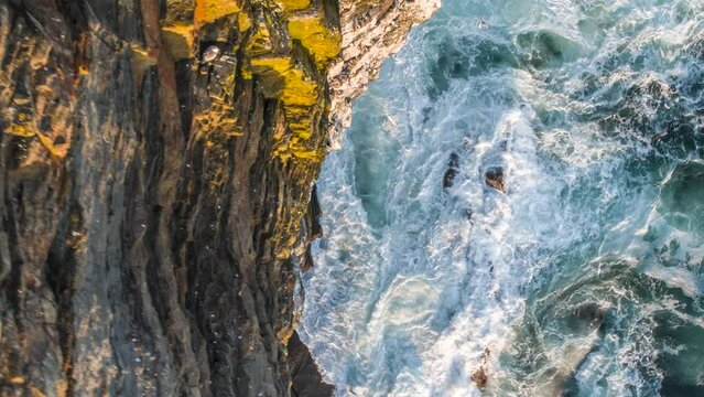 Aerial view of waves crashing along Kilkee Cliffs coastline, Knockroe, County Clare, Ireland.