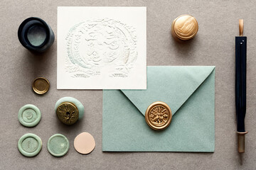 Mock up flat lay of stationary. Includes watercolor card or paper, a pastel blue envelope, an ornate wax seal. Tools used to create are shown on a bright background, adapted from generative ai.
