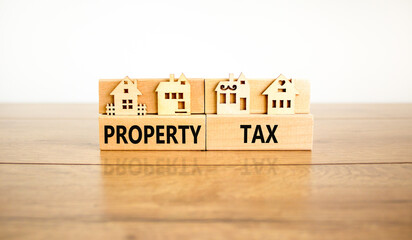 Property tax symbol. Concept words Property tax on wooden blocks. Beautiful wooden table white background. House models on wooden blocks. Business and property tax concept. Copy space.