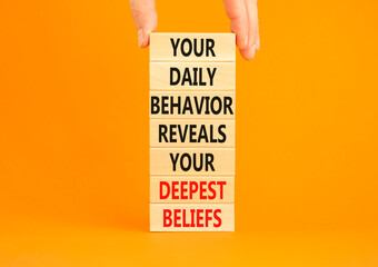 Behavior symbol. Concept words Your daily behavior reveals your deepest beliefs on wooden blocks. Beautiful orange background. Copy space. Businessman hand. Motivational business behavior concept.