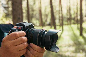 Fototapeta premium Holds a camera in his hand in the forest