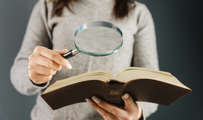 Woman looking at a bible with a magnifying glass
