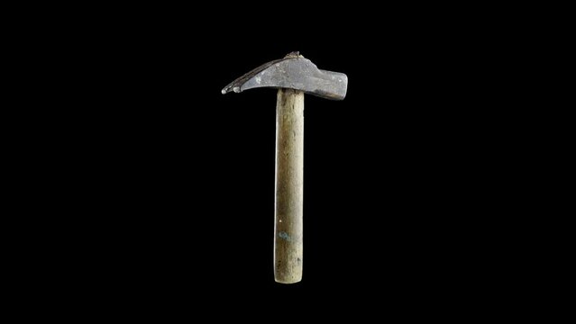Vintage building tool hammer with old long wooden handle and large metal head rotates on deep black background close view