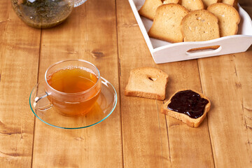 Obraz na płótnie Canvas Tea in a glass cup on the wooden table and toast with plum jam.