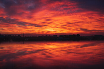 Fototapeta na wymiar dramatic sunset reflection, orange and cloudy sky
