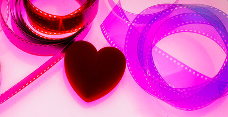 heart on a pink background with film strip. cinematography filmmaking show business concept