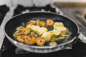 Shrimps fried in butter in frying pan for spicy chilli sauce dish. Restaurant kitchen food preparation process. Horizontal indoor shot. High quality photo
