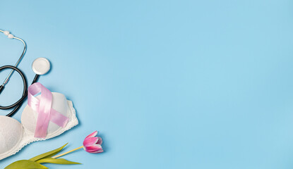 One pink ribbon, tulip, bra and stethoscope on a blue background.