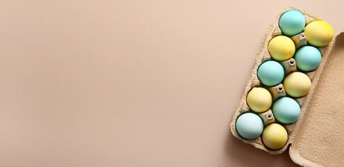 Cardboard holder with painted Easter eggs on beige background with space for text