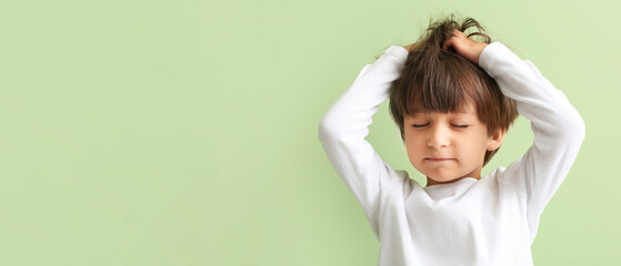 Little boy suffering from head ache on green background with space for text