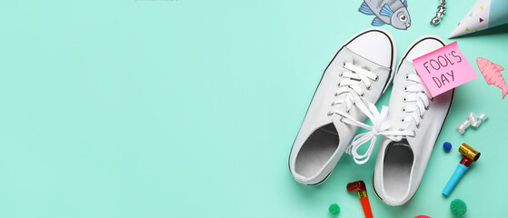 Pair of shoes, sticky note with text FOOL'S DAY and party decor on color background with space for text