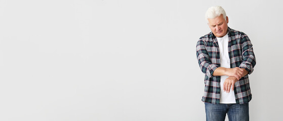Senior man suffering from Parkinson syndrome on light background with space for text