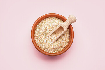 Bowl of amaranth seeds and scoop on pink background