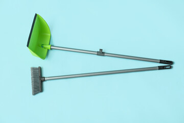 Broom with plastic dustpan on color background