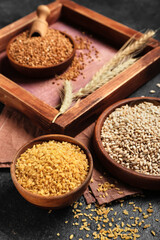 Bowls with pearl barley and bulgur on dark background, closeup