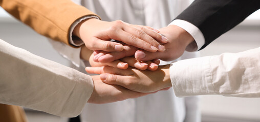 Obraz na płótnie Canvas Business partners. Group of people holding hands together in office, closeup. Banner design