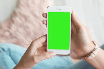 Chroma key compositing. Woman holding smartphone with green screen indoors, closeup. Mockup for design