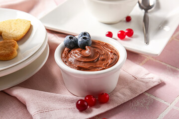 Bowl of delicious chocolate pudding with blueberry on pink tile table