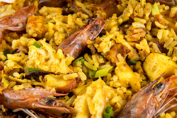 Classic Spanish dish. Spanish paella with prawns, octopus, squid, mussels, onion, tomato, garlic, olive oil and lemon. Assembled on white plate.