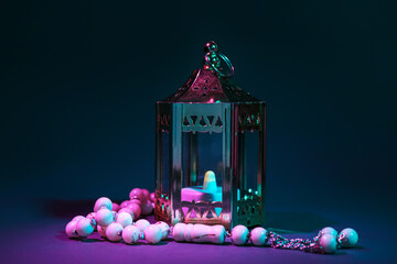 Muslim lantern with candle and prayer beads for Ramadan on dark background