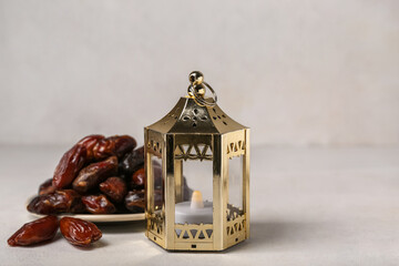 Muslim lantern with candle and dates for Ramadan on light background