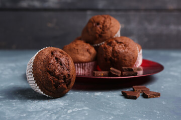 Plate with delicious chocolate muffins on grey grunge table