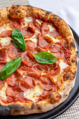 Classic pepperoni pizza decorated with basil leaf