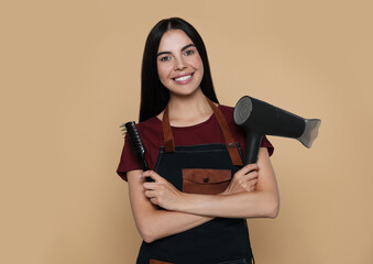 Portrait of happy hairdresser with hairdryer and vent brush on beige background