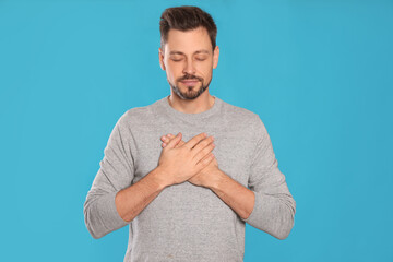 Man with clasped hands praying on turquoise background