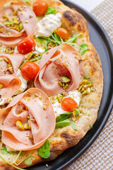 Neapolitan pizza with ham, arugula and cherry tomato