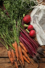 Different vegetables and net bag on wooden table, flat lay