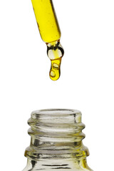 Dripping yellow facial serum from pipette into glass bottle on white background, closeup
