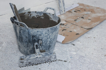 Bucket with cement and putty knifes indoors. Home improvement
