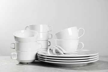 Set of clean dishware on grey table against light background