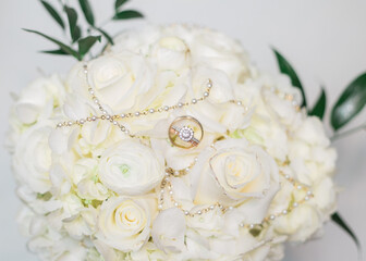 wedding bouquet of roses with jewelry placed on top 