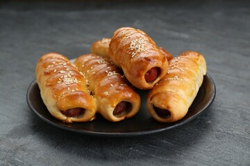 Plate with delicious sausage rolls on grey table