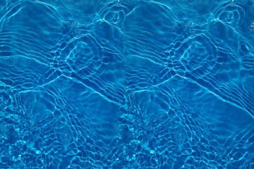 Defocus blurred transparent blue colored clear calm water surface texture with splashes and bubbles. Trendy abstract nature background. Water waves in sunlight with copy space. Blue watercolor shining