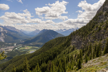 Mountain landscape - coniferous forest, beautiful blue sky with clouds. Summer tourism - ski lift to the mountain. Banff, Alberta, Canada. 