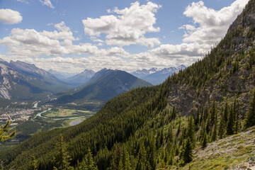 Fototapeta na wymiar Mountain landscape - coniferous forest, beautiful blue sky with clouds. Summer tourism - ski lift to the mountain. Banff, Alberta, Canada. 