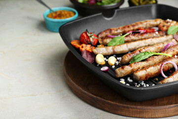 Grill pan with tasty sausages and vegetables on light table, closeup. Space for text