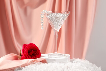 Martini glass with pearl beads and red rose on pink cloth