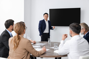Business conference. Group of people listening to speaker report near tv screen in meeting room - obrazy, fototapety, plakaty