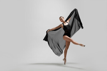 Graceful young ballerina practicing dance moves with black veil on light grey background. Space for text