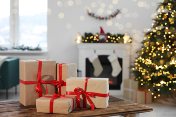Many different gift boxes on wooden table against blurred festive lights in living room, space for text. Christmas presents