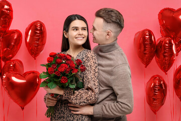 Happy couple celebrating Valentine's day. Beloved woman holding bouquet of roses near heart shaped...