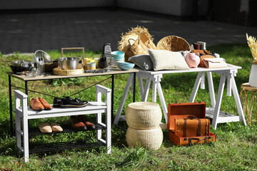 Small tables with many different items on garage sale in yard