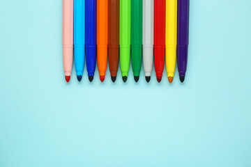 Different colorful markers on light blue background, flat lay. Space for text