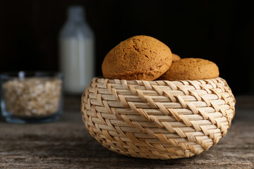 Wicker basket with delicious oatmeal cookies on wooden table. Space for text
